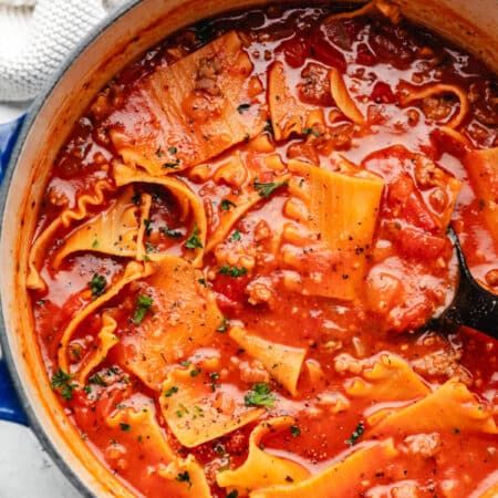 A blue cast iron Dutch oven filled with lasagna soup.