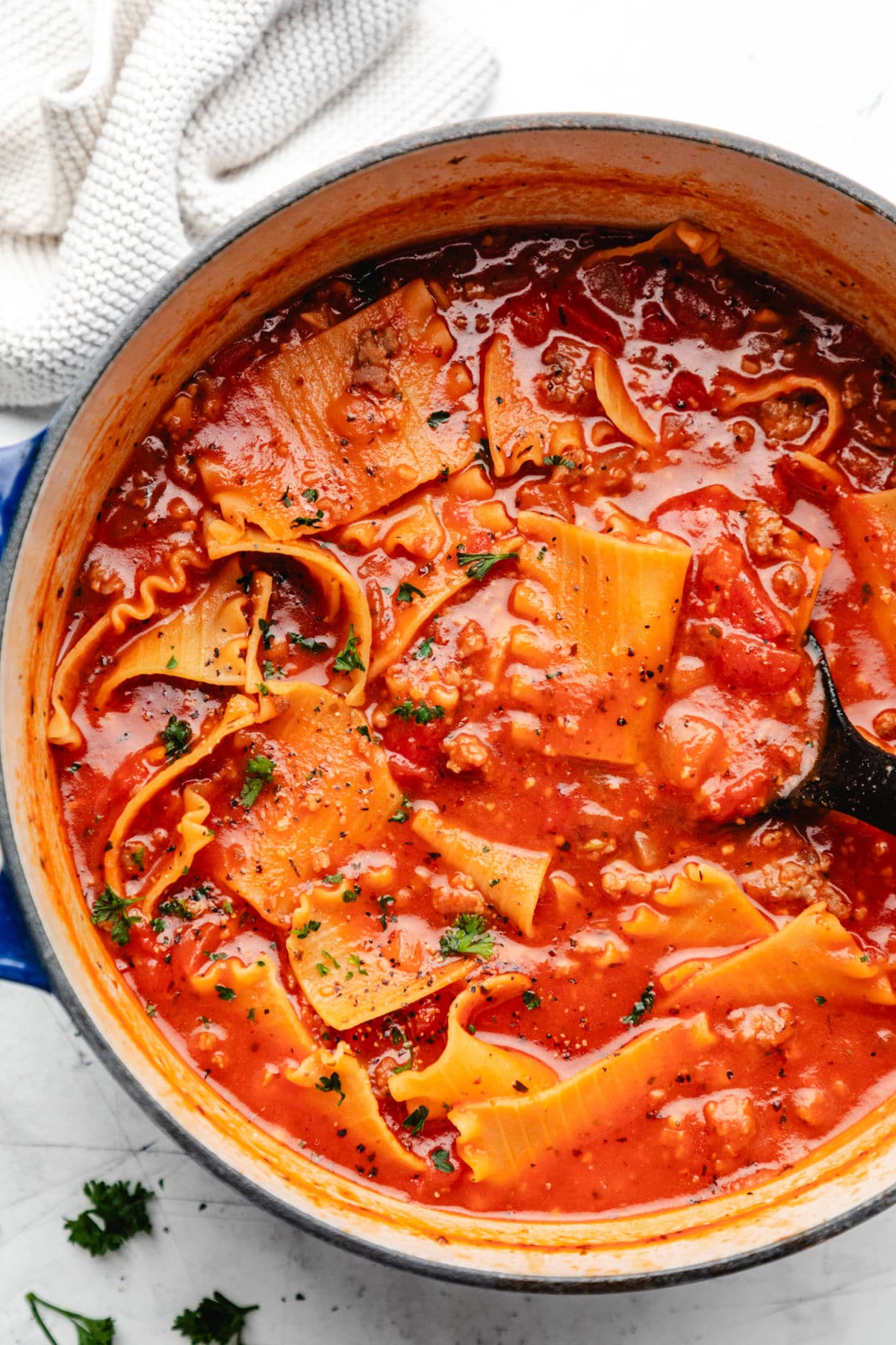 A blue cast iron Dutch oven filled with lasagna soup. 