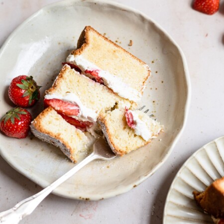 A fork taking a bite of strawberry shortcake cake.
