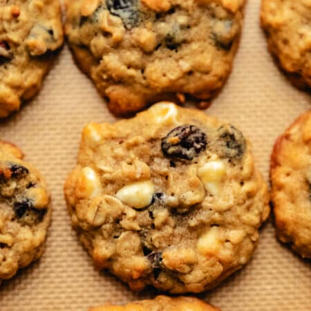 Rows of cranberry oatmeal cookies on a silicone baking mat