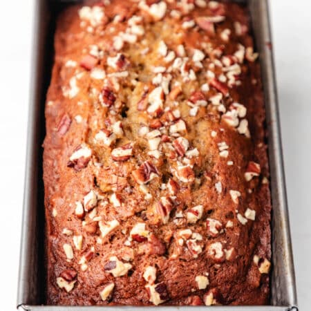 A loaf of banana nut bread in a metal loaf pan.