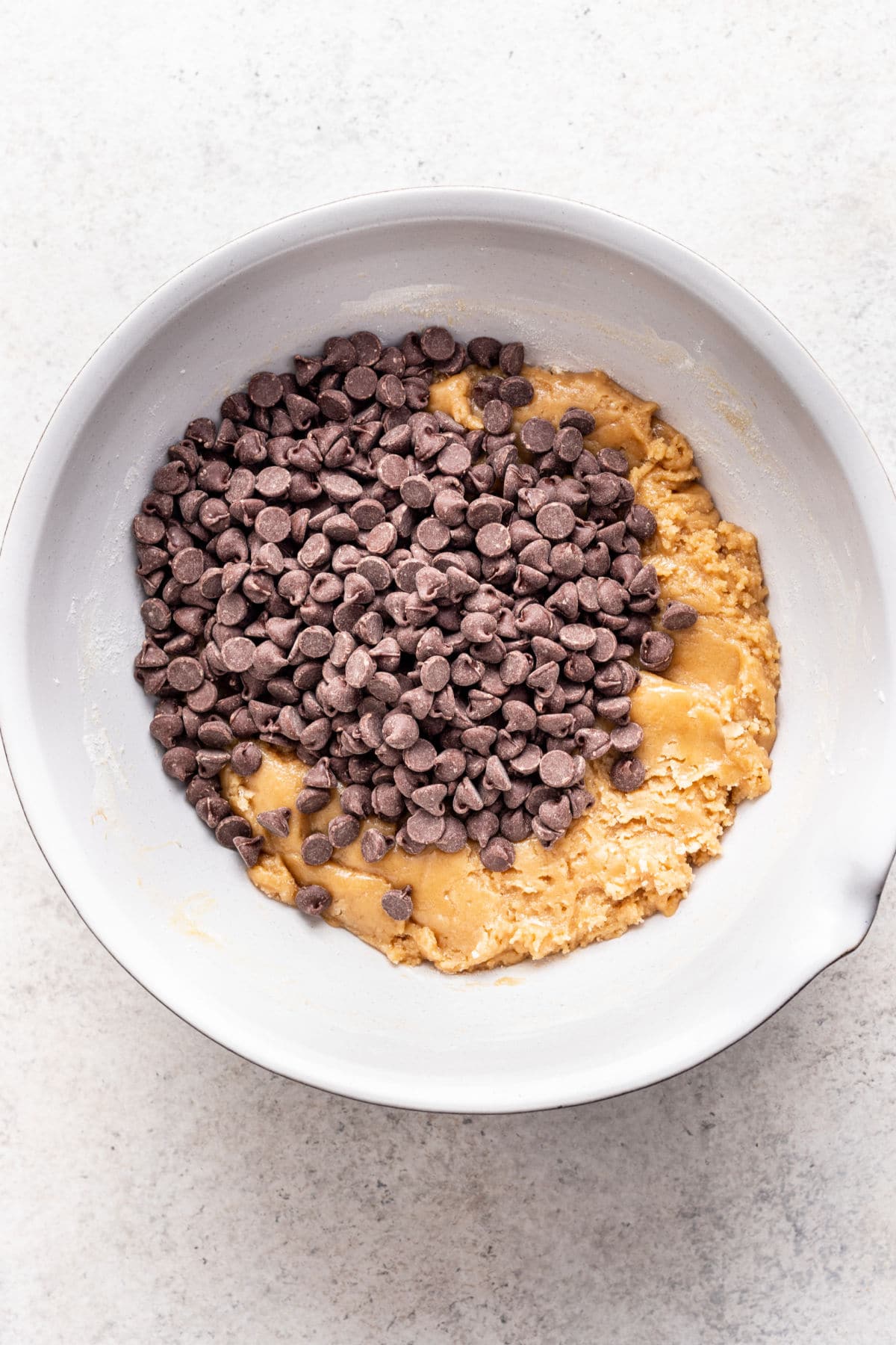 Chocolate chips sitting on top of a bowl of cookie dough.