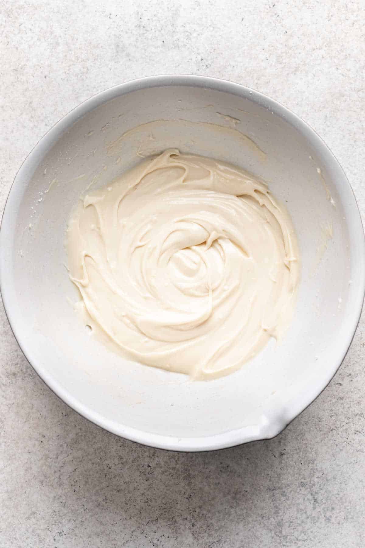 Glaçage au fromage à la crème dans un bol de mélange blanc.