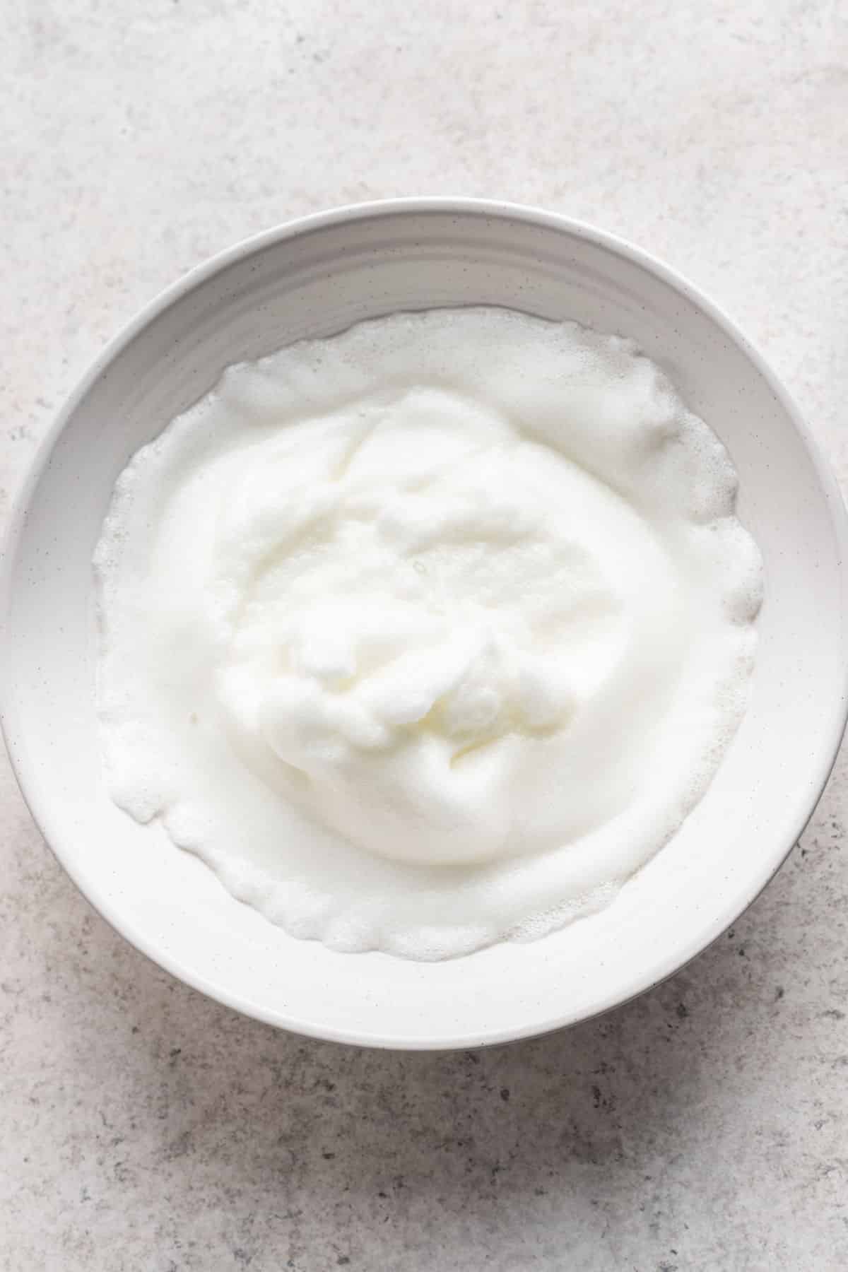 Soft peak egg whites in a mixing bowl. 