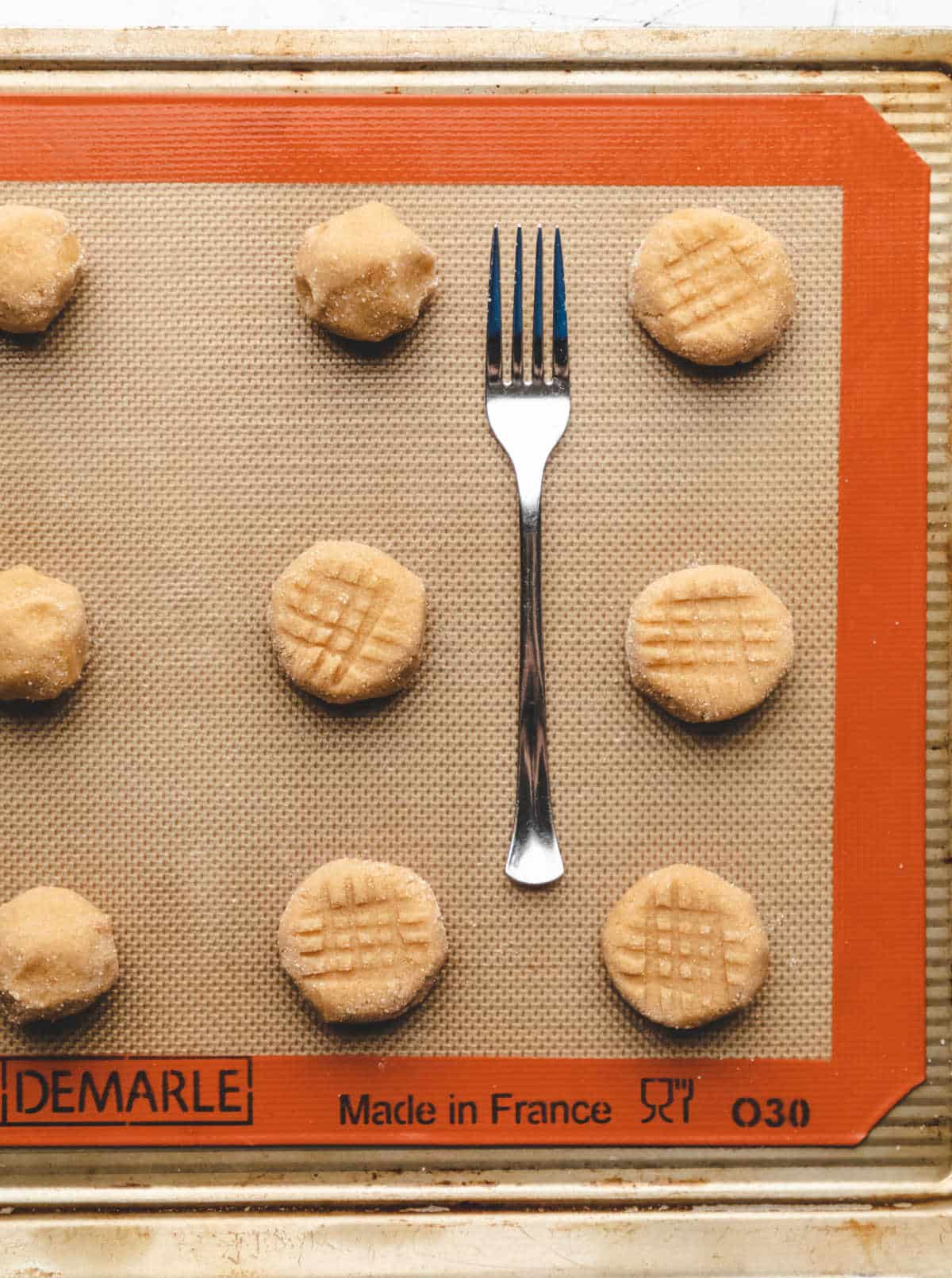 A fork next to rows of peanut butter cookie dough with a crosshatch design.