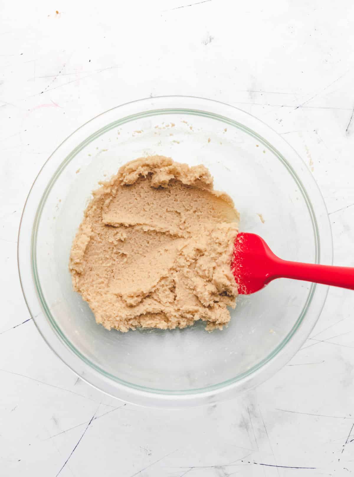 Creamed butter and sugars in a glass mixing bowl. 