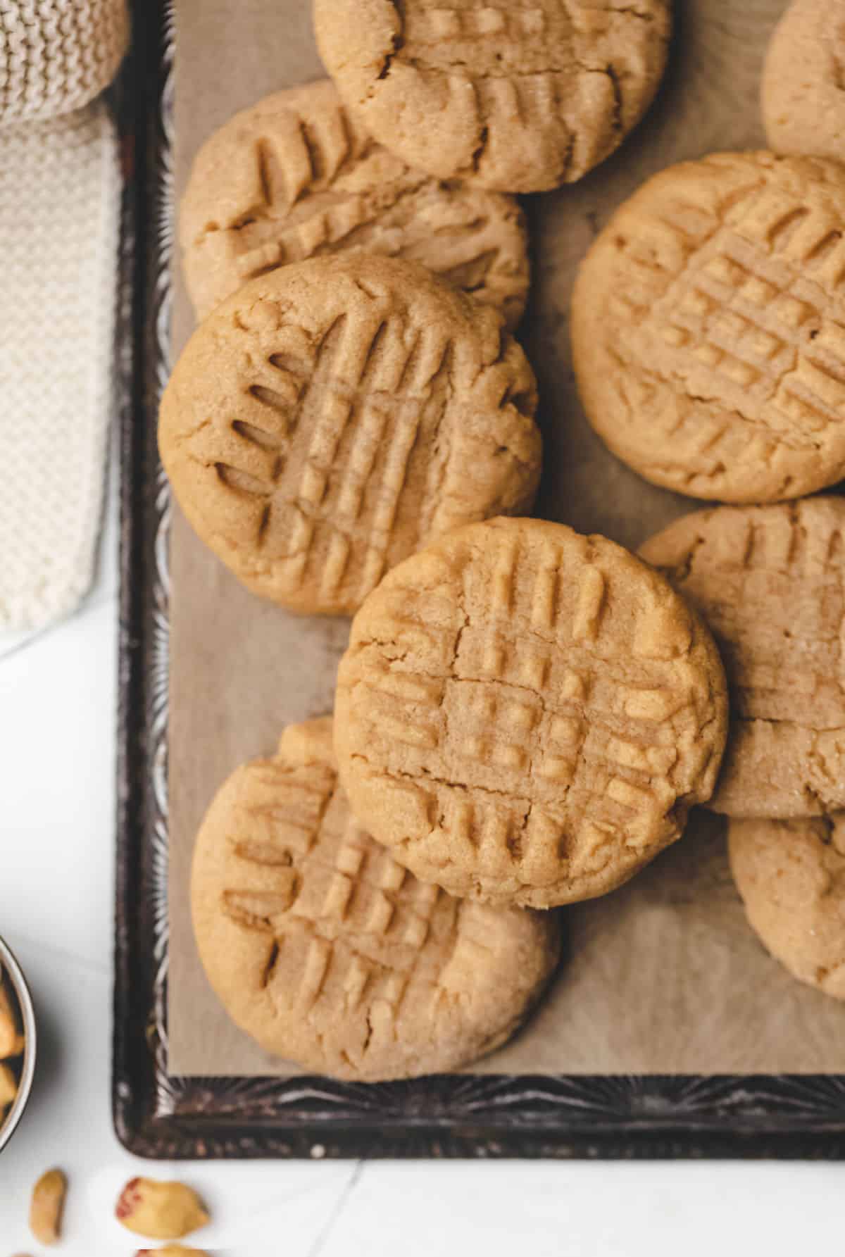 Overlapping peanut butter cookies on a piece of brown parchment paper.