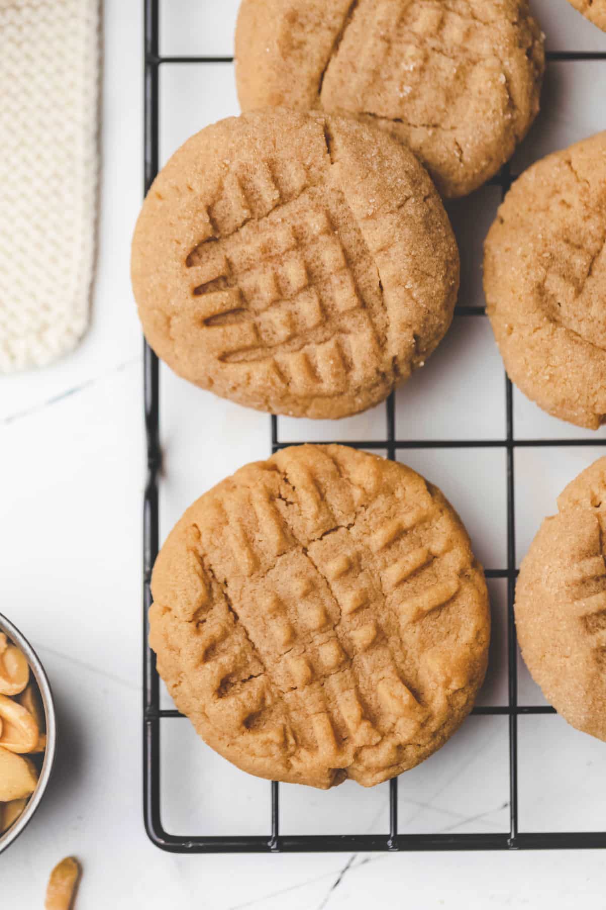 Overlapping peanut butter cookies on a black metal cooling rack. 