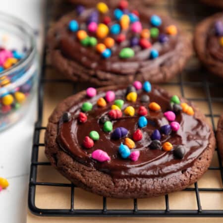 A row of cosmic brownie cookies on a black wire cooling rack.