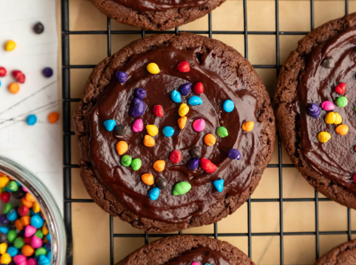 Cosmic brownie cookies next to a dish of rainbow candy coated chocolate pieces. 