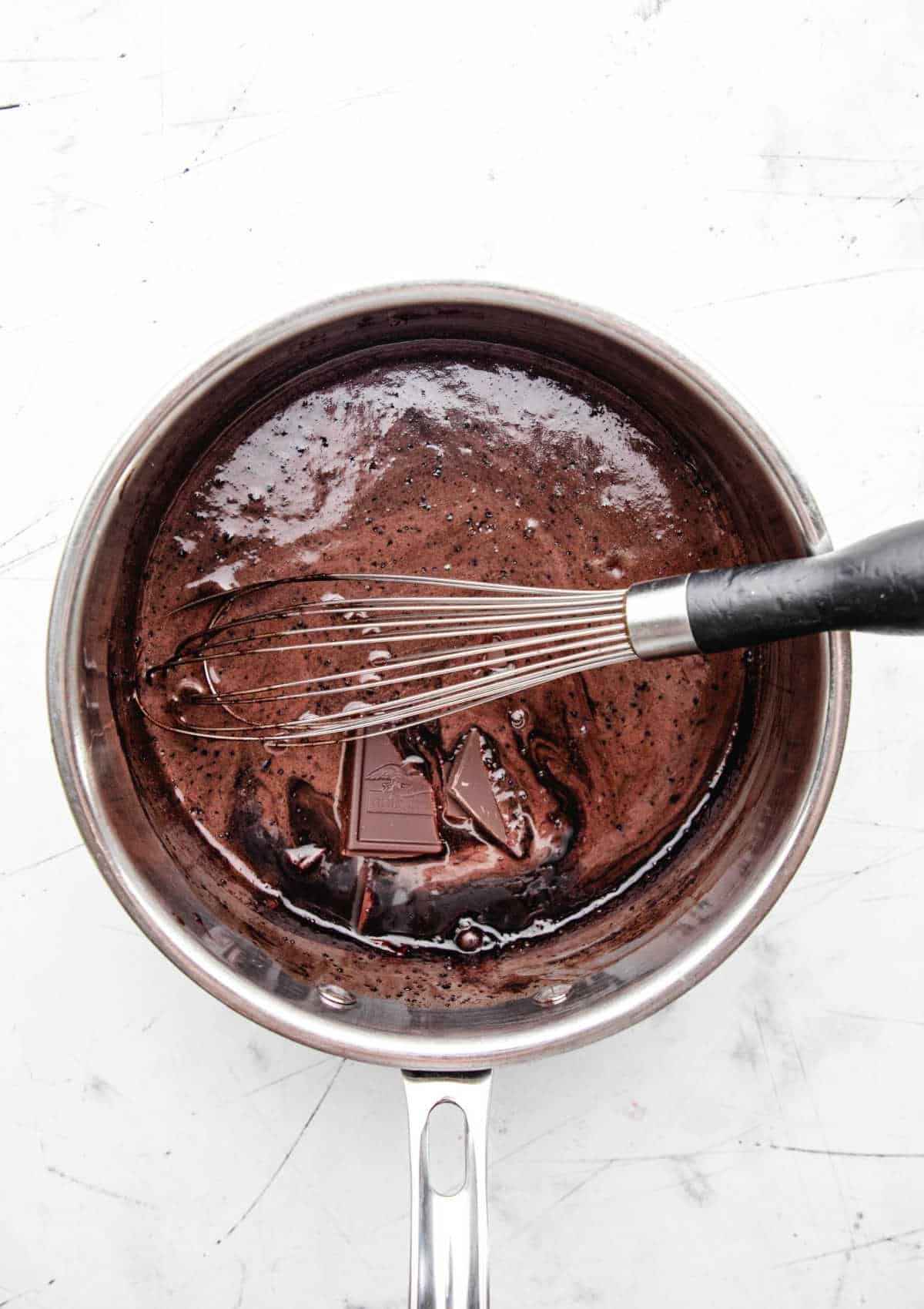 A whisk stirring chopped chocolate into chocolate heavy cream mixture. 