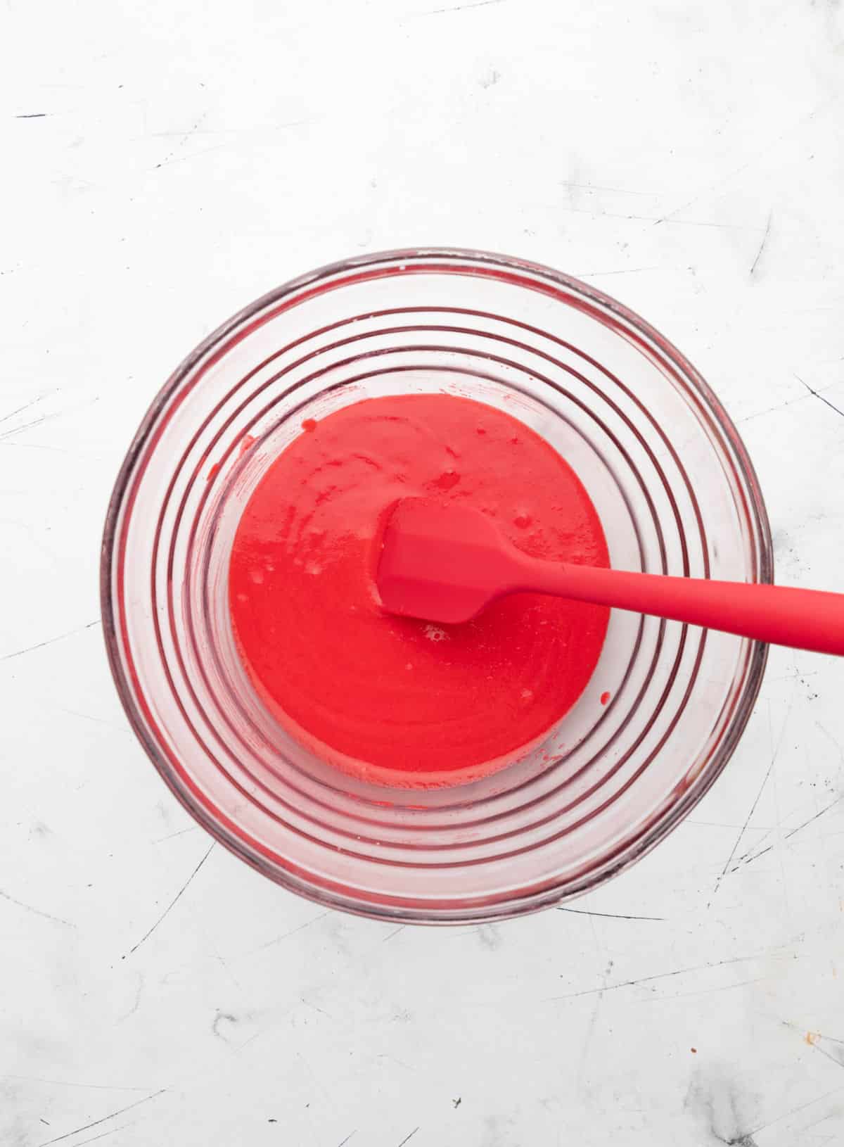 Strawberry gelatin powder and Greek yogurt mixed together in a glass mixing bowl. 