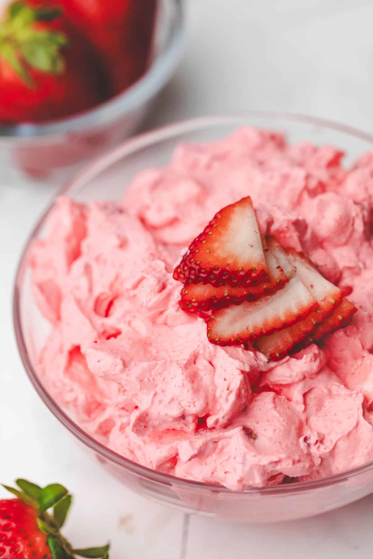 A bowl of strawberry fluff topped with sliced fresh strawberries.