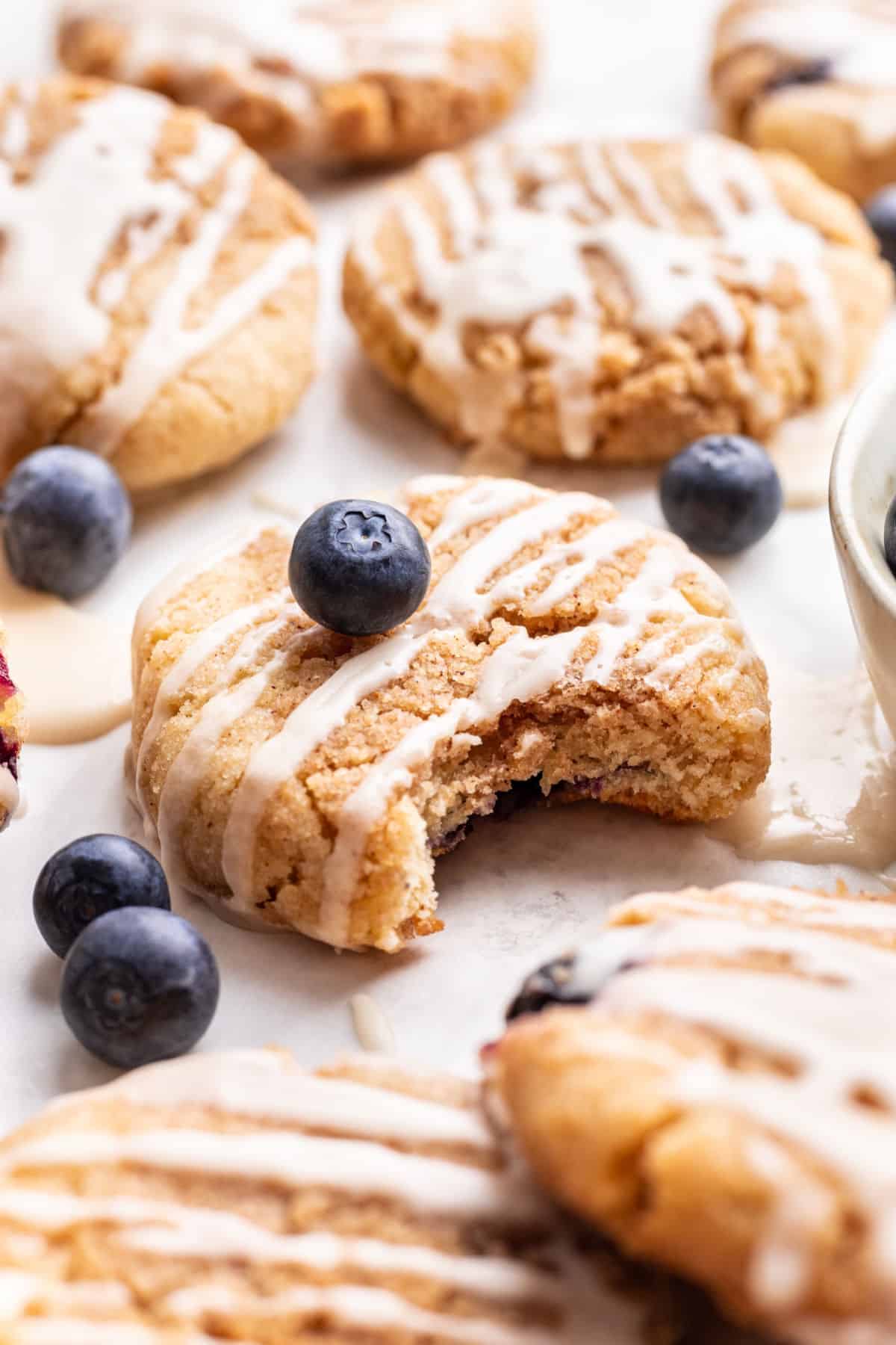 A blueberry muffin cookie with a bite missing in the middle of more cookies. 