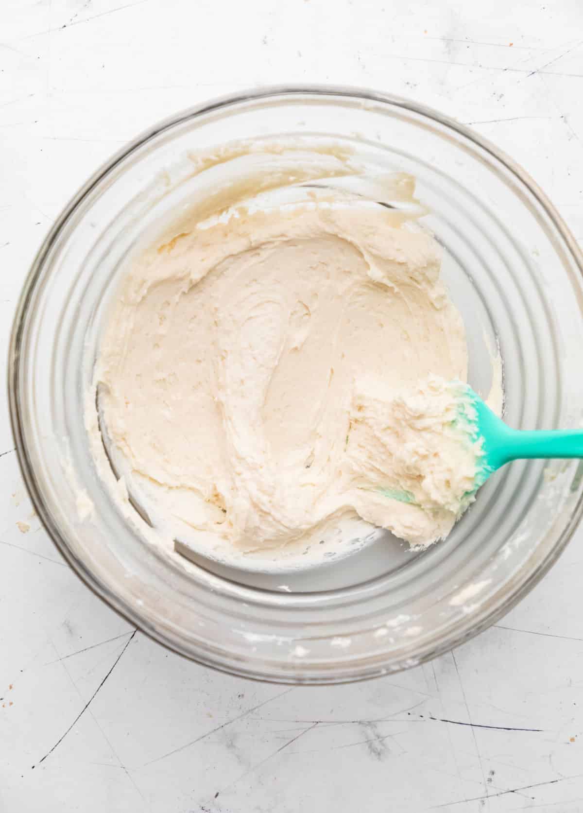 Buttercream frosting in a glass mixing bowl. 