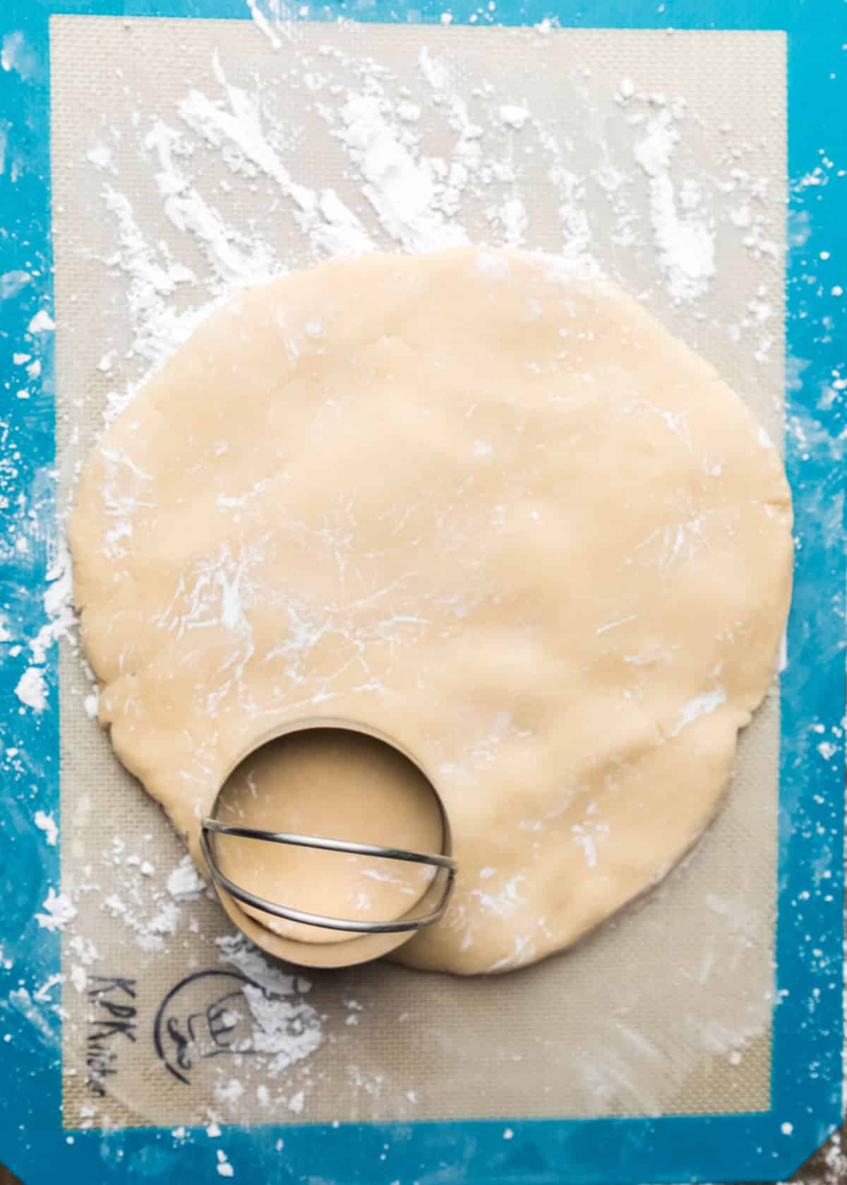 A round cookie cutter cutting cookie dough. 