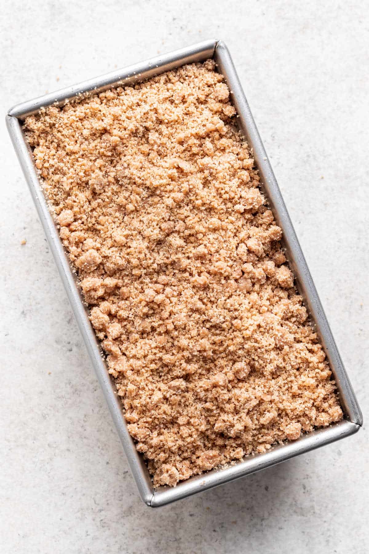 Brown sugar crumble on top of cake batter in a loaf pan.
