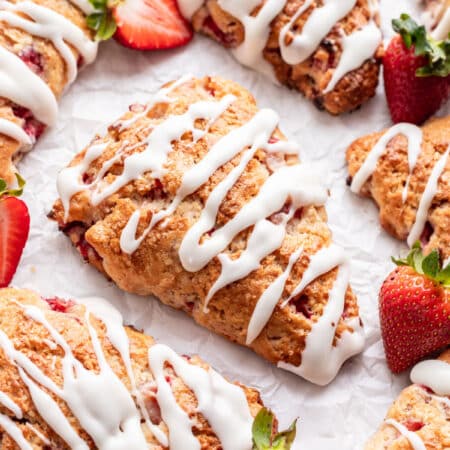 Strawberry scones surrounded by fresh cut strawberries.