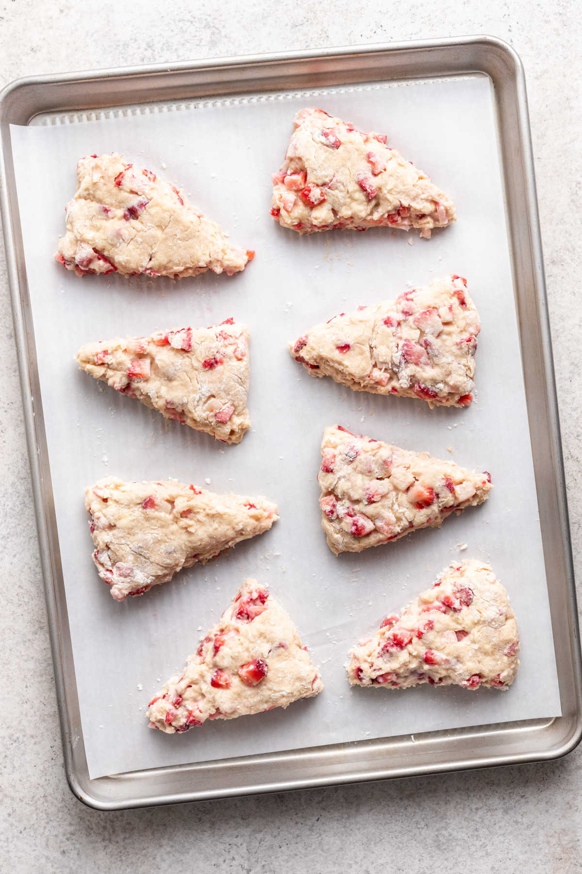Unbaked strawberry scones on a baking tray.