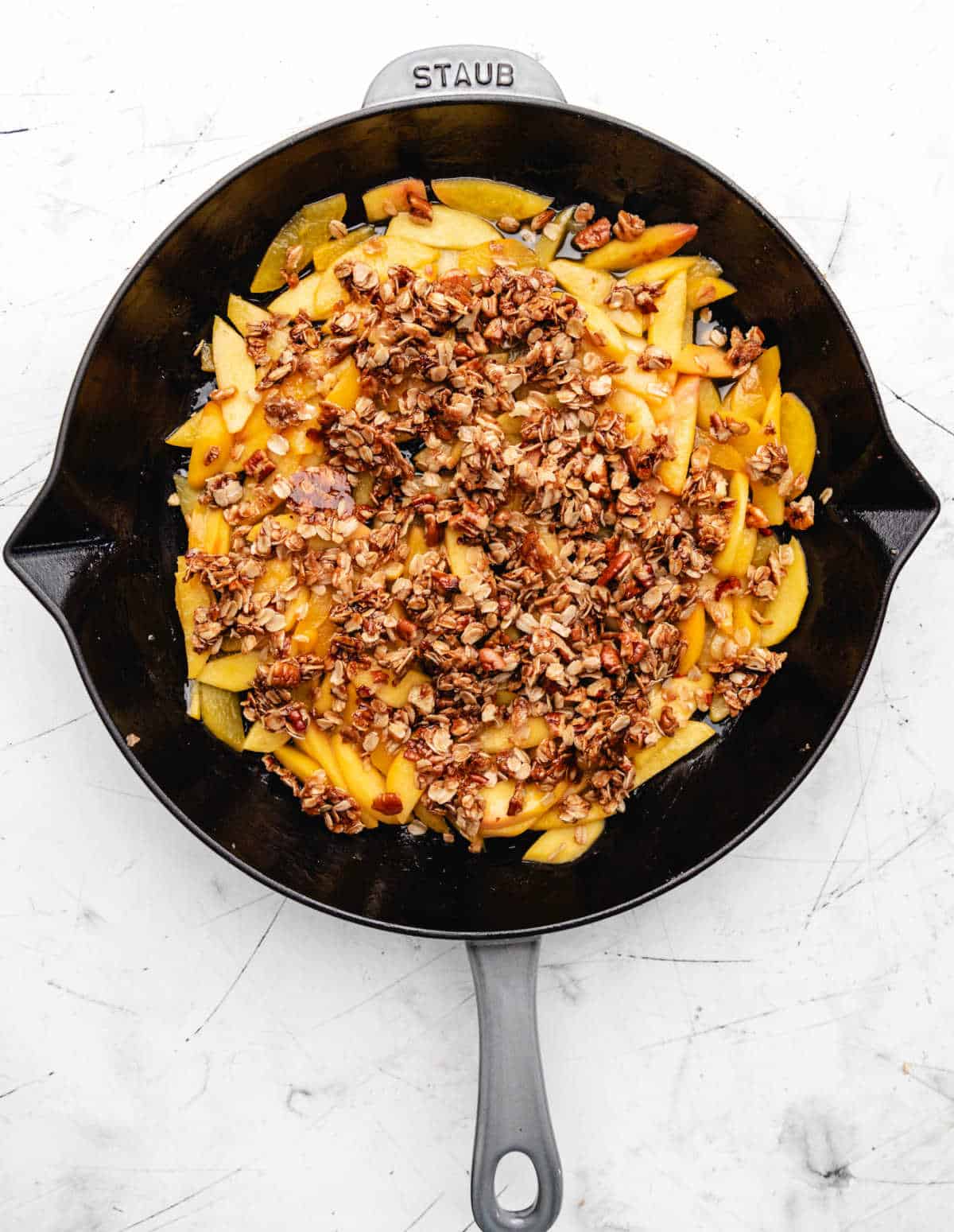 A gray skillet with peach crisp in it. 