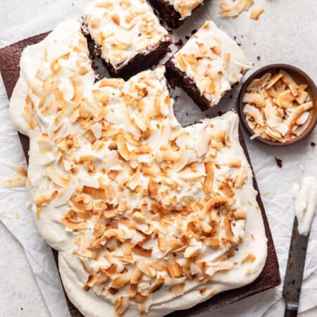 Chocolate coconut sheet cake with three pieces cut.