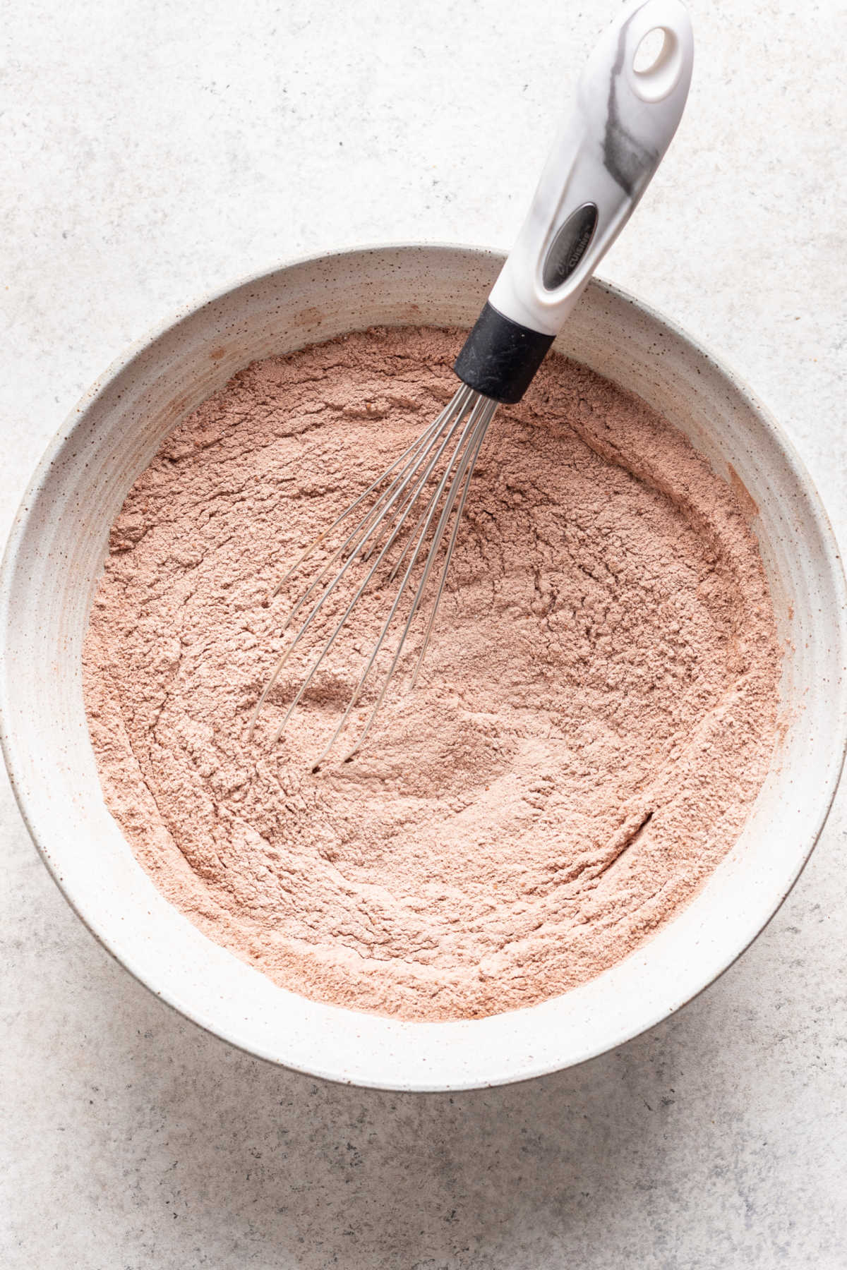 Dry ingredients for chocolate coconut cake in a white mixing bowl. 