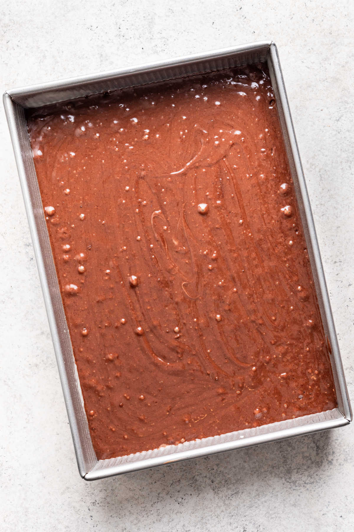 Chocolate coconut cake batter in a baking pan.