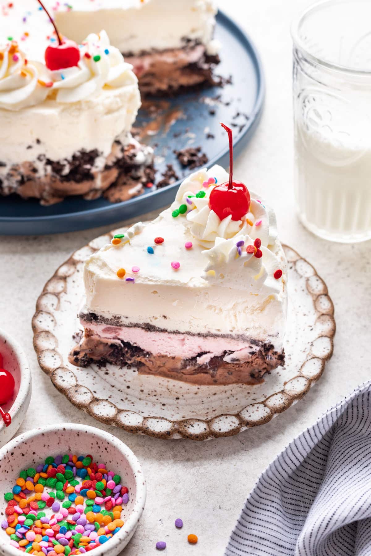 A slice of homemade ice cream cake on a plate next to the cake.