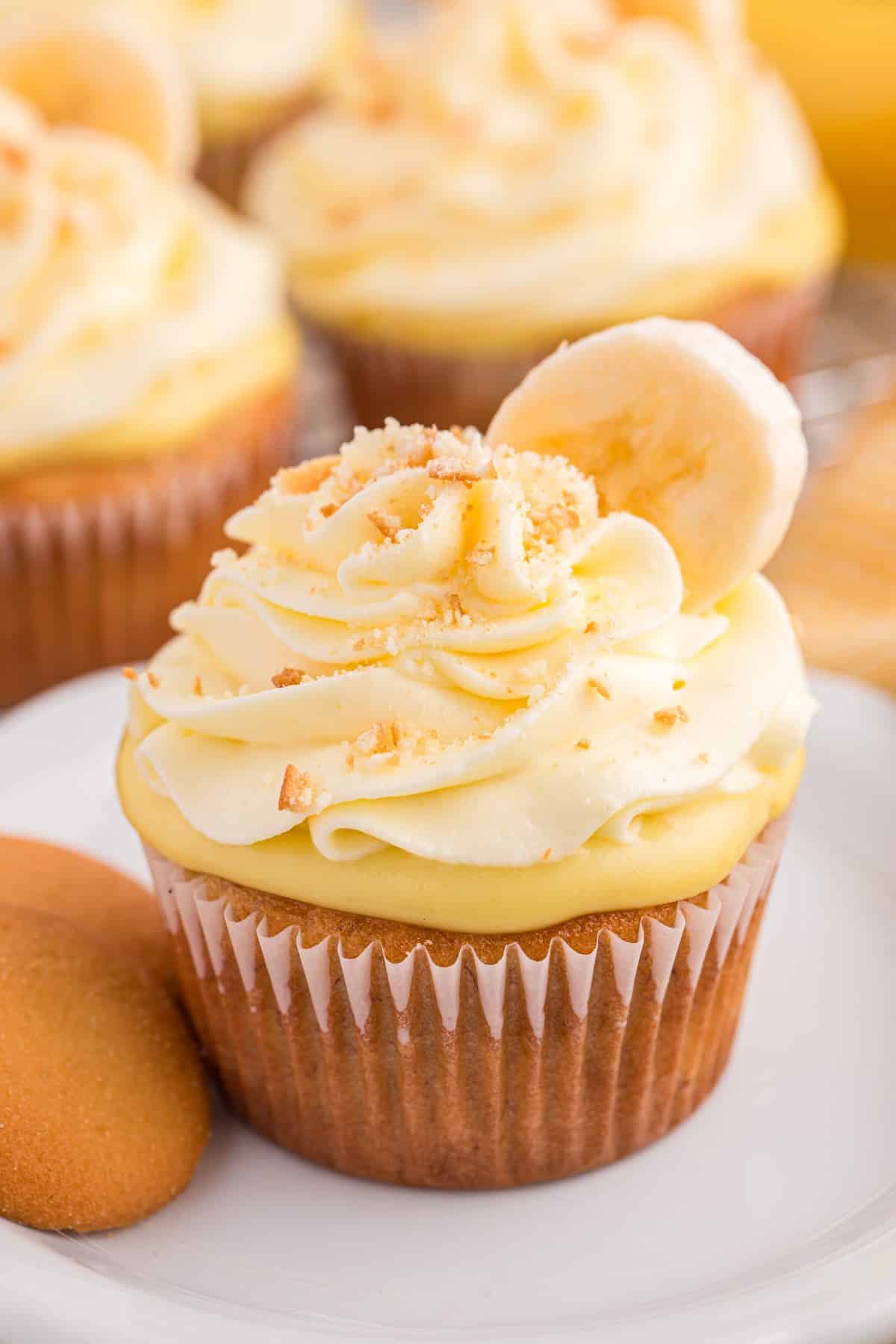 Un cupcake au pudding à la banane sur une assiette blanche à côté d'un nilla wafer.