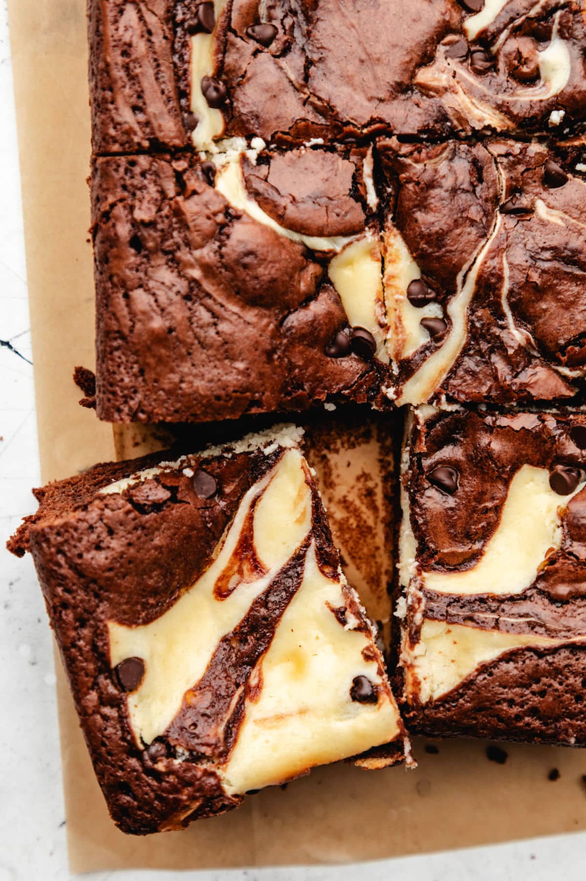 A cut cheesecake brownie slightly at an angle next to the brownies.