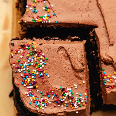 A spatula holding a frosted piece of chocolate sheet cake.