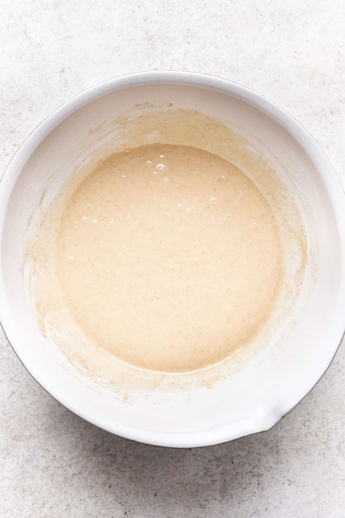 Apple upside down cake batter in a white mixing bowl. 