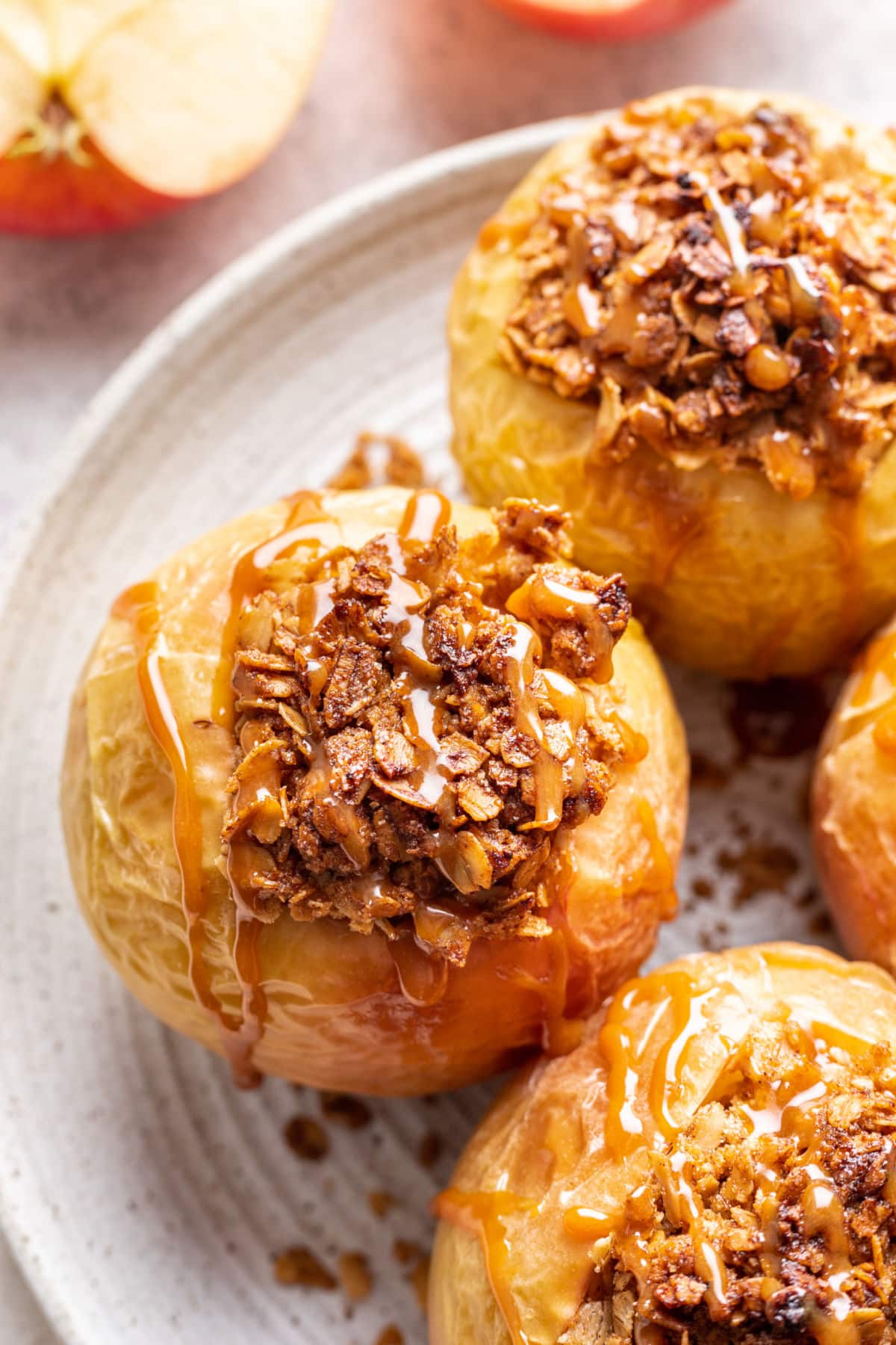 Close up of a baked apple drizzled with caramel next to a sliced apple.