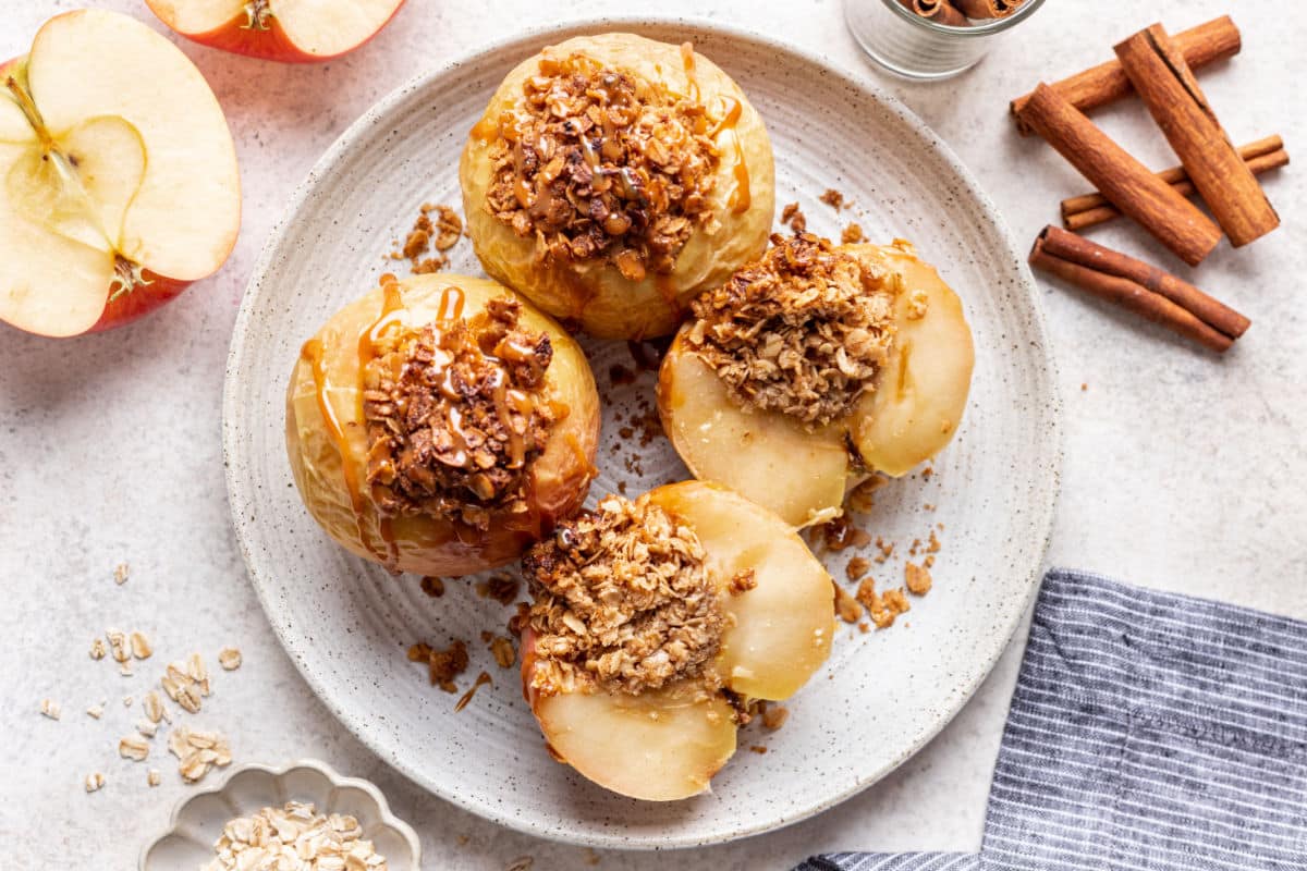 Baked apples on a white plate with one of the apples cut in half. 