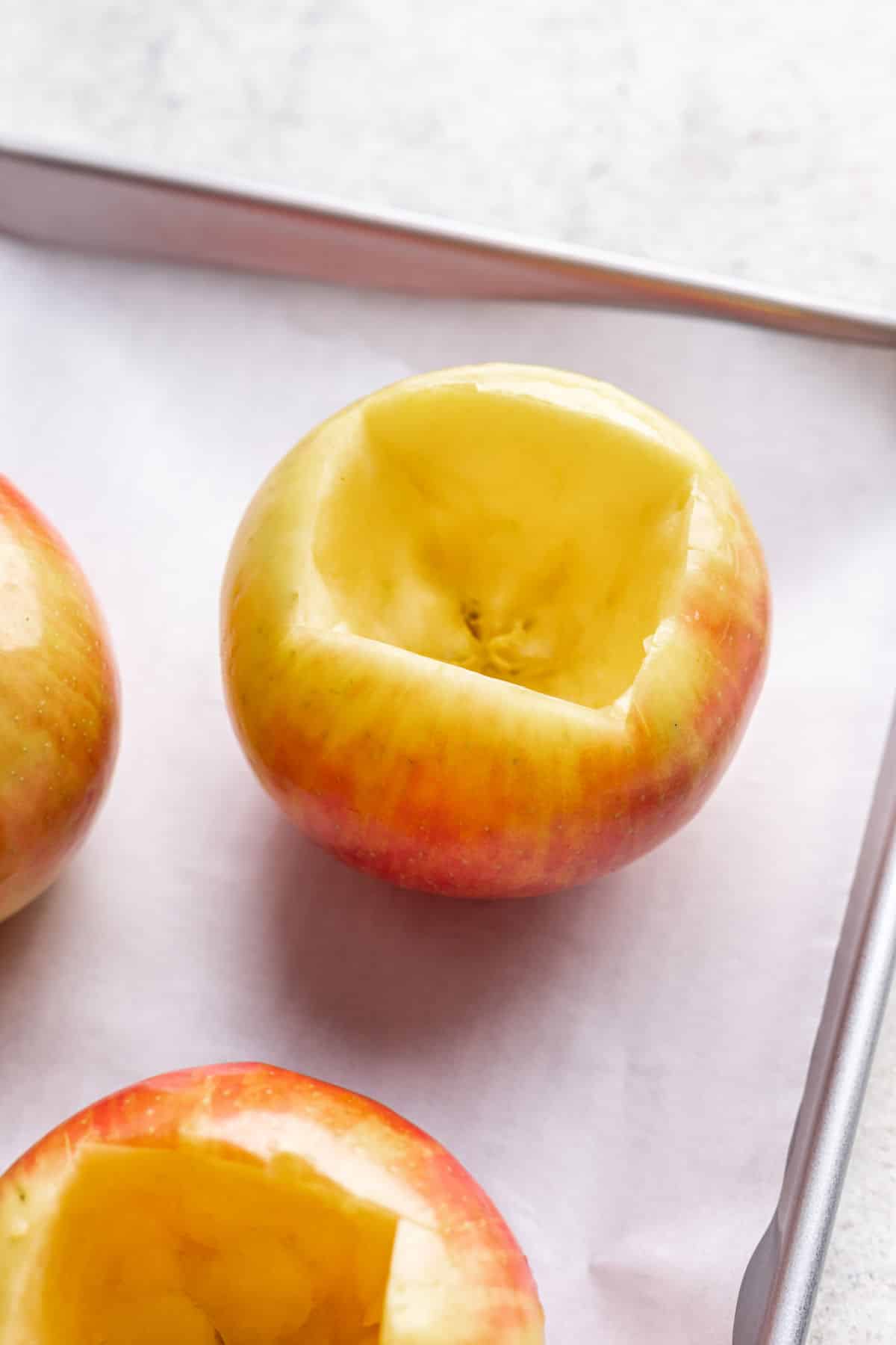 A hollowed out apple on a baking sheet. 