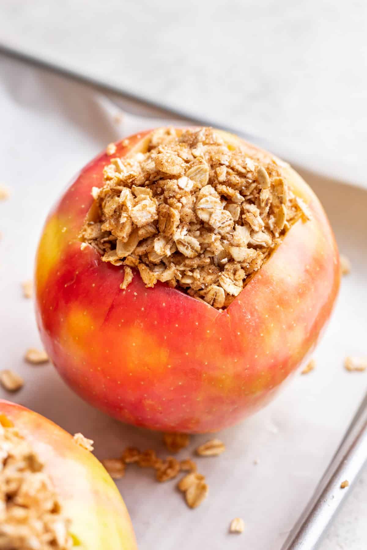 Hollowed out apples filled with oatmeal mixture on a baking sheet. 