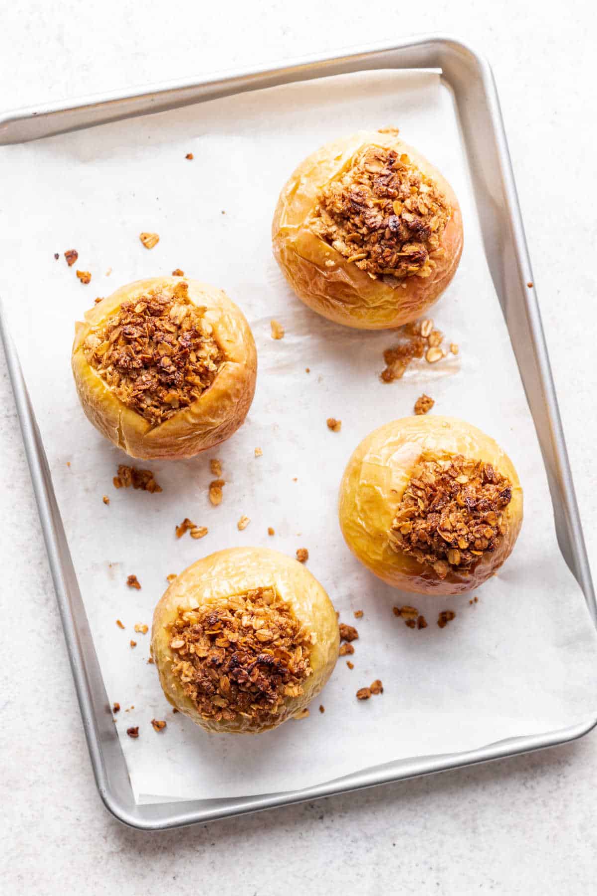 Baked apples on a parchment lined baking sheet. 