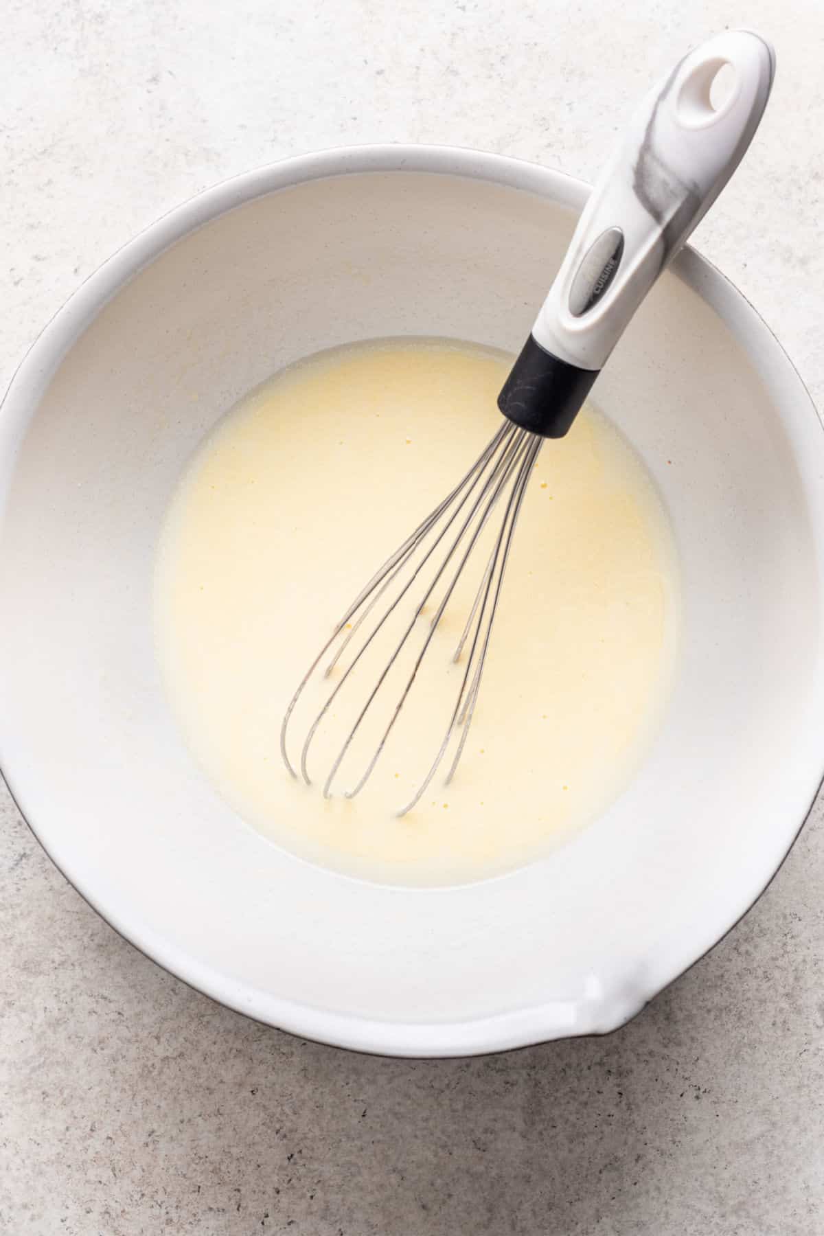 Oil eggs and buttermilk whisked together in a white mixing bowl. 