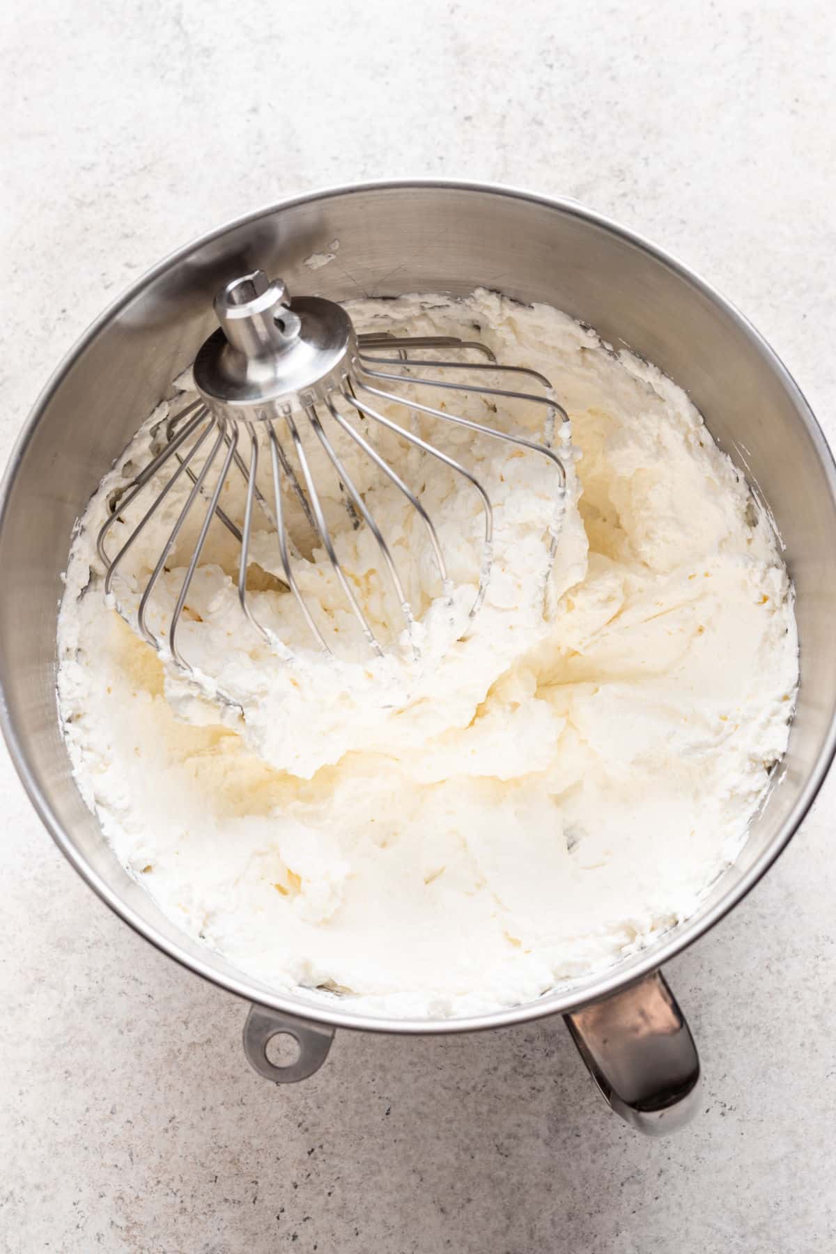 Whipped cream in a silver mixing bowl. 