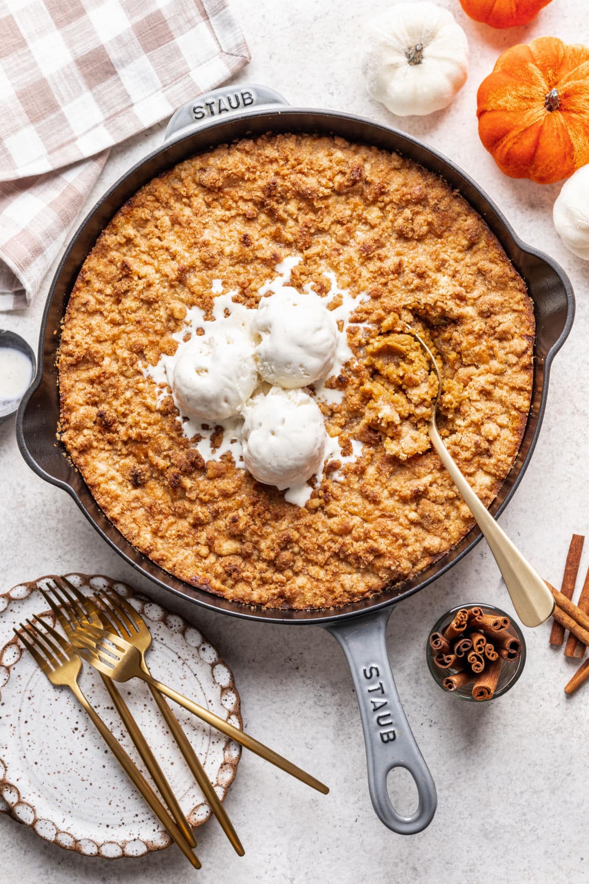 A gold spoon in a skillet of pumpkin crisp. 