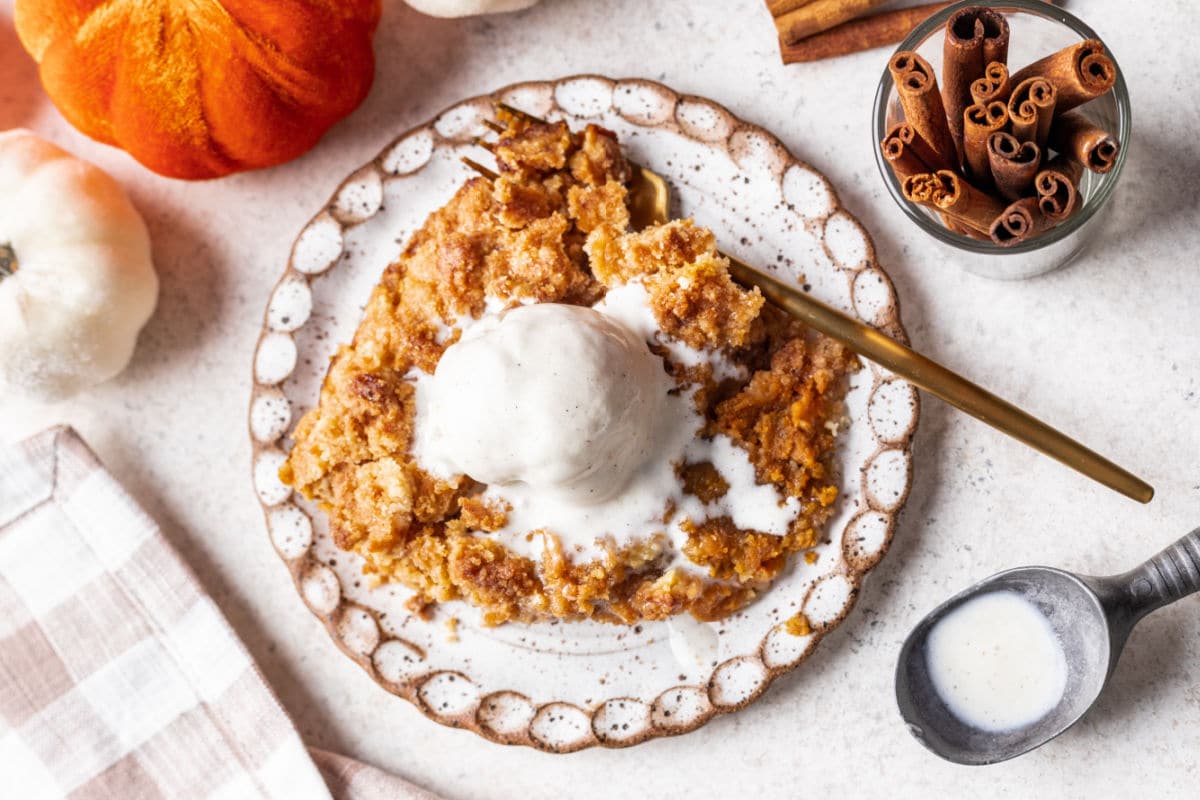 A speckled plate with pumpkin crisp and a scoop of vanilla ice cream. 