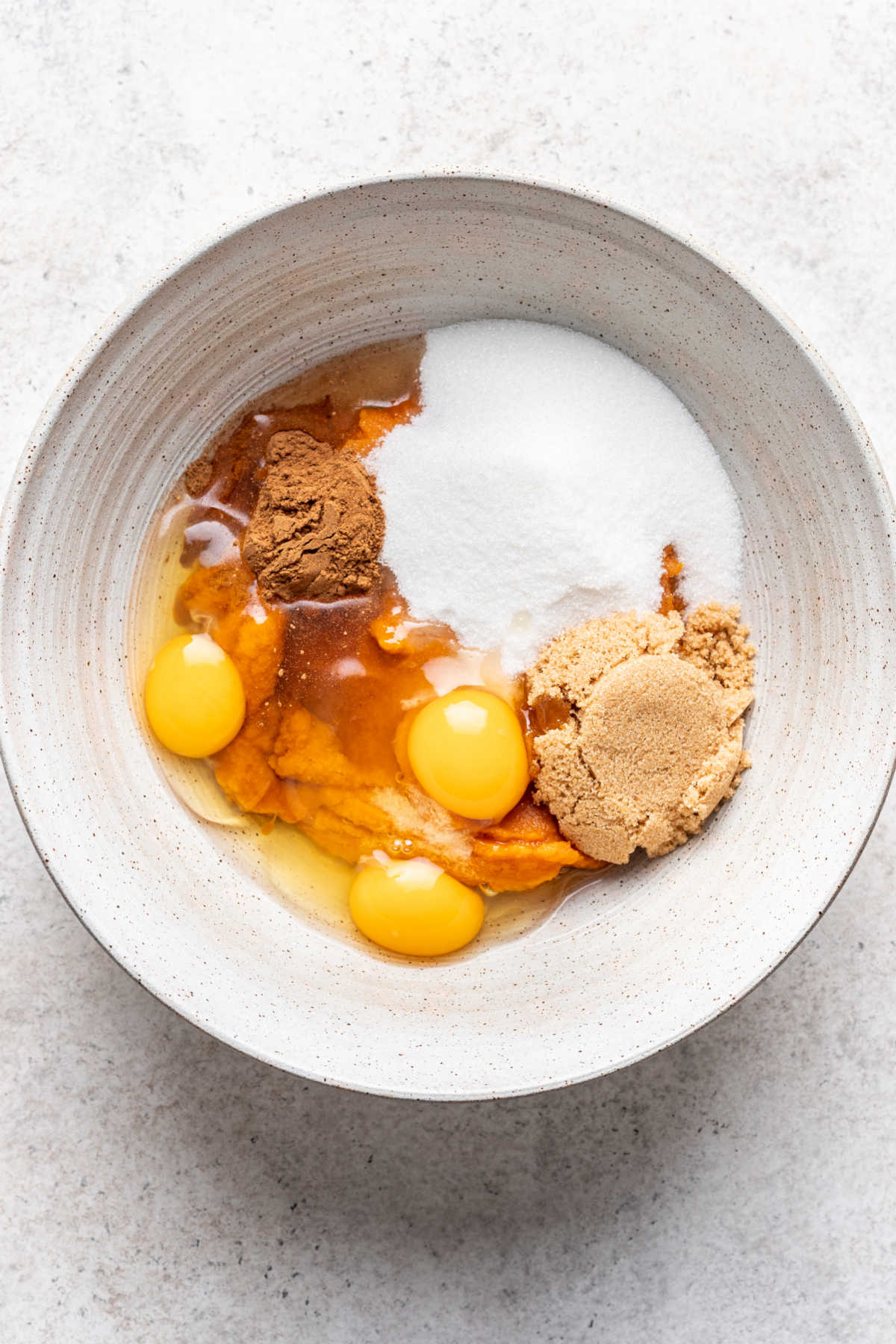 Eggs pumpkin sugar and spices in a mixing bowl. 