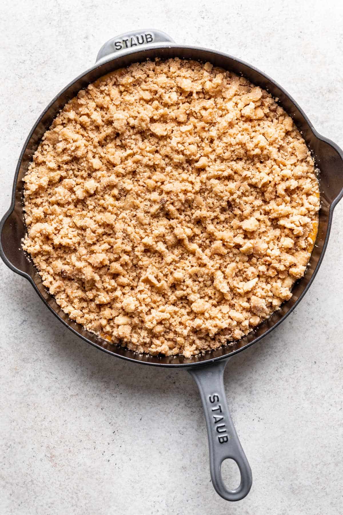 Crumble topping on pumpkin crisp filling in a skillet. 