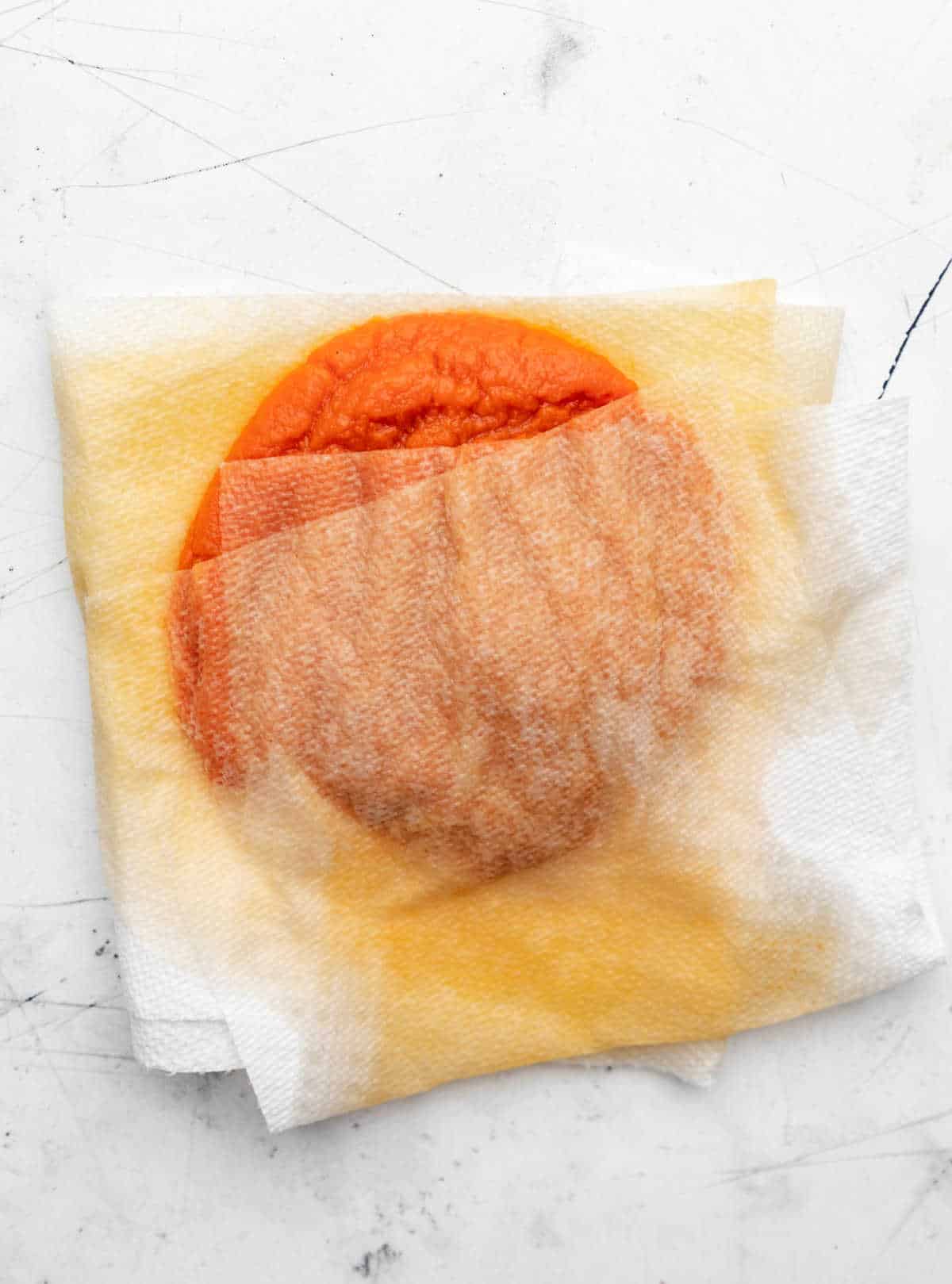 Paper towels blotting moisture from pumpkin puree.