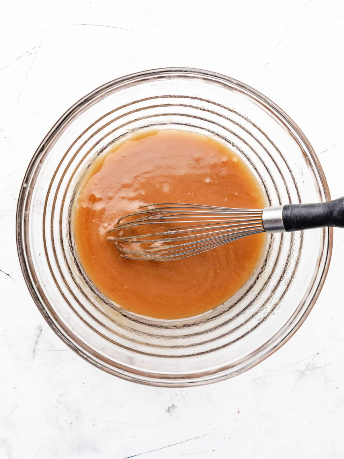 Melted butter and sugars in a glass mixing bowl. 