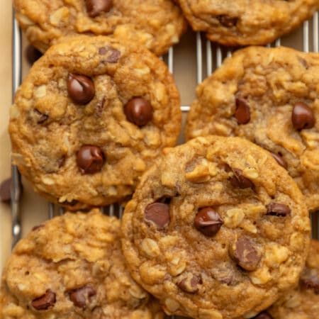 Overlapping pumpkin oatmeal cookies on a wire rack.