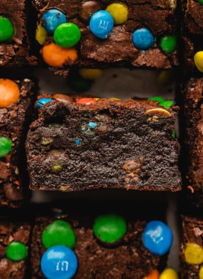 A row of cut M&M brownies with the middle brownie on its side.