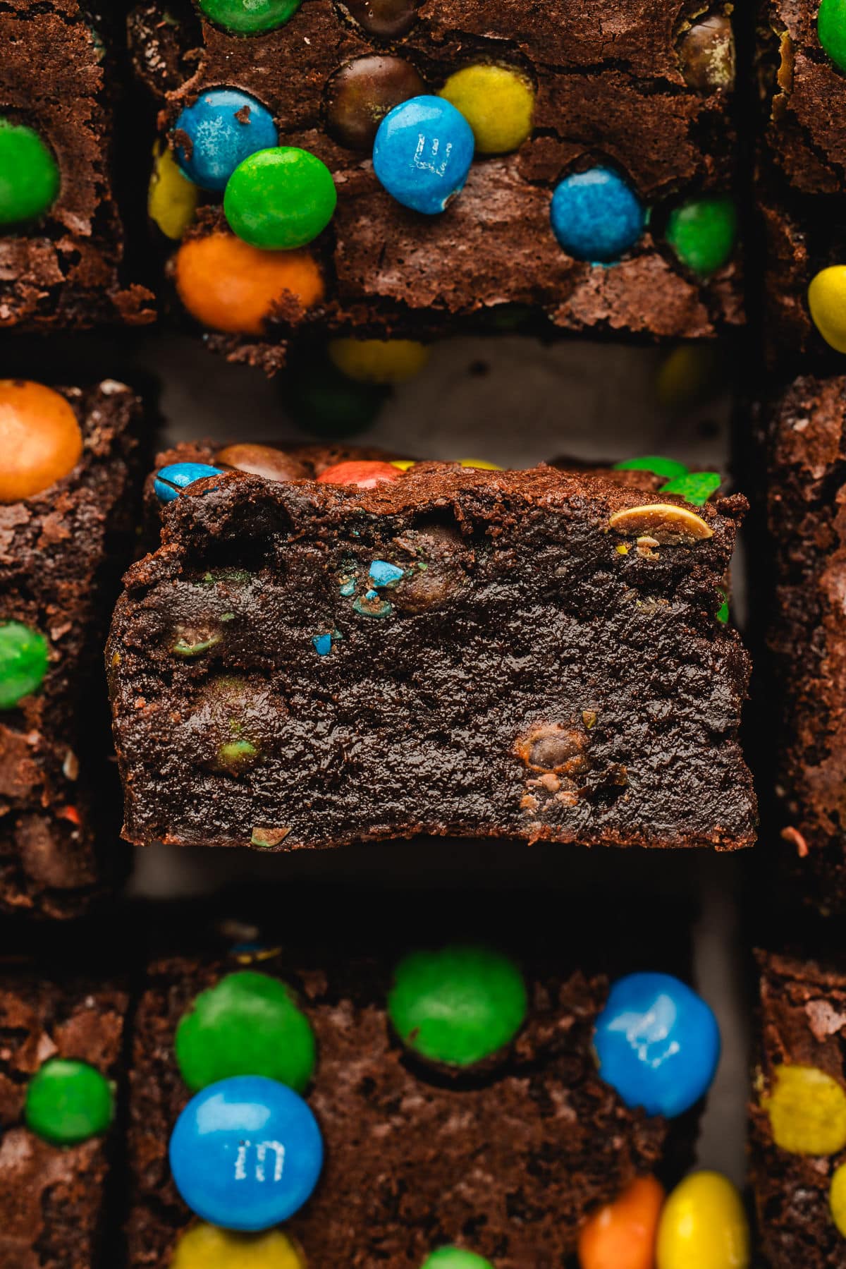 Une rangée de brownies M&M coupés avec le brownie du milieu sur le côté.