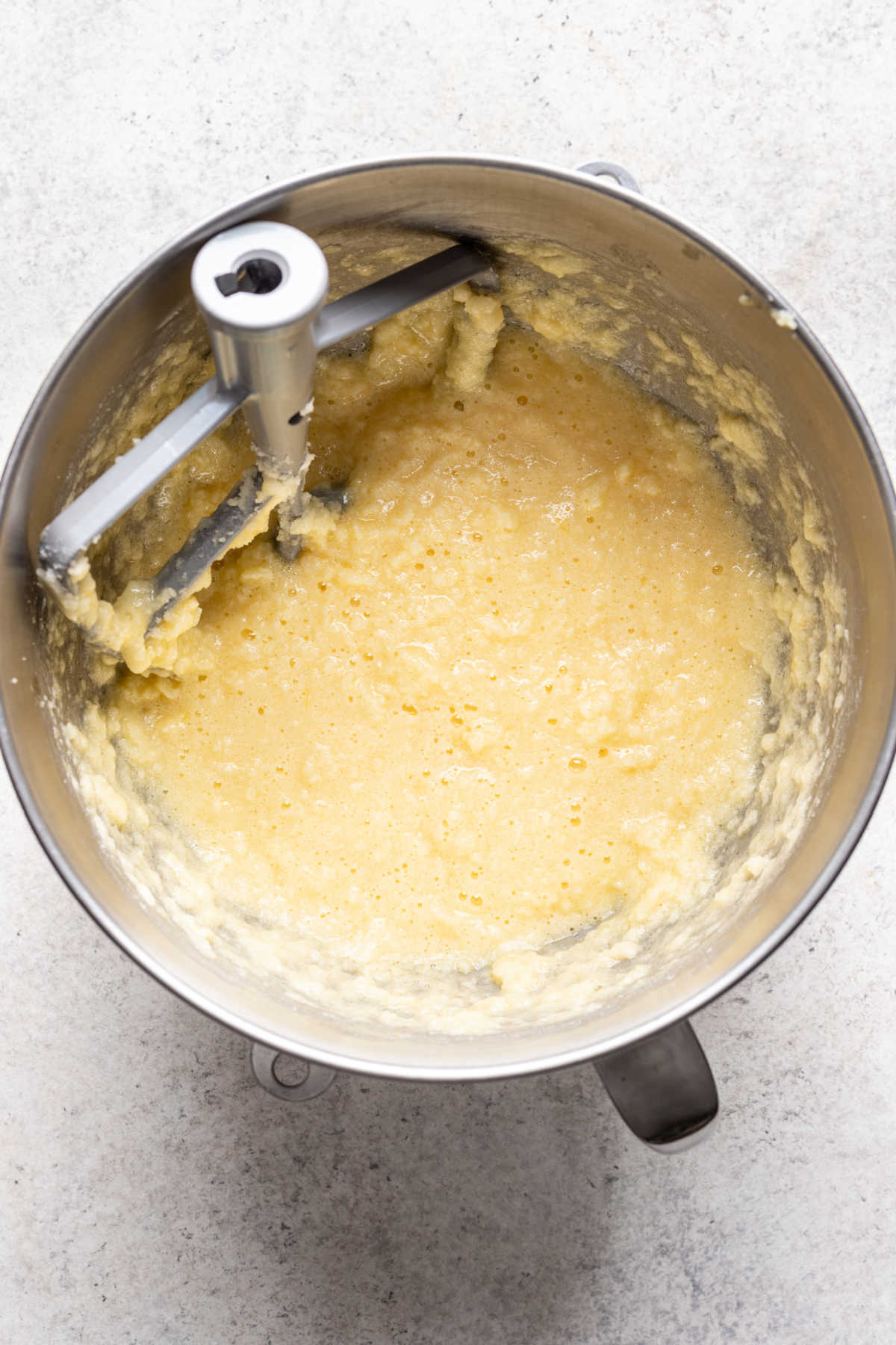 Eggs beaten into creamed butter and sugar mixing in a silver mixing bowl. 