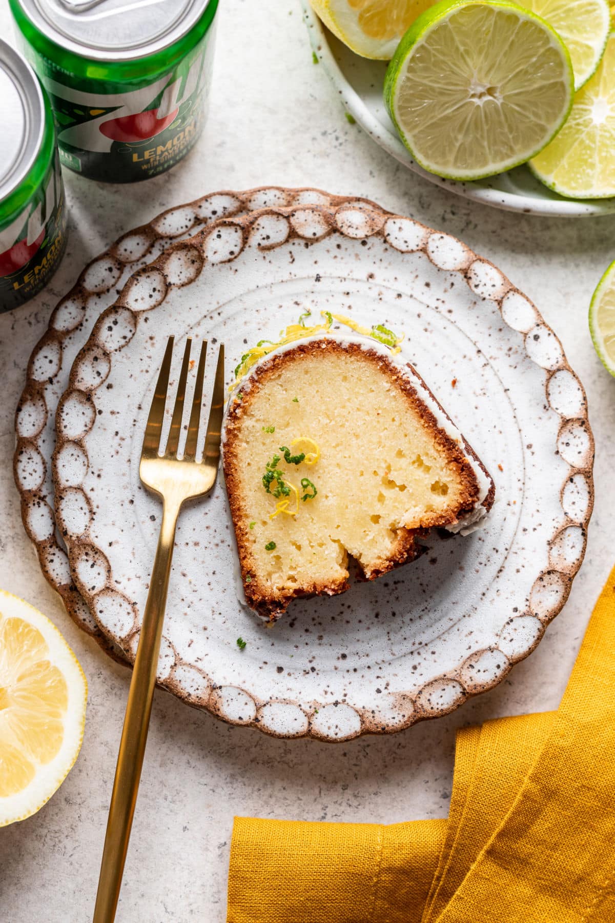 A slice of 7 up pound cake on a plate with a gold fork. 